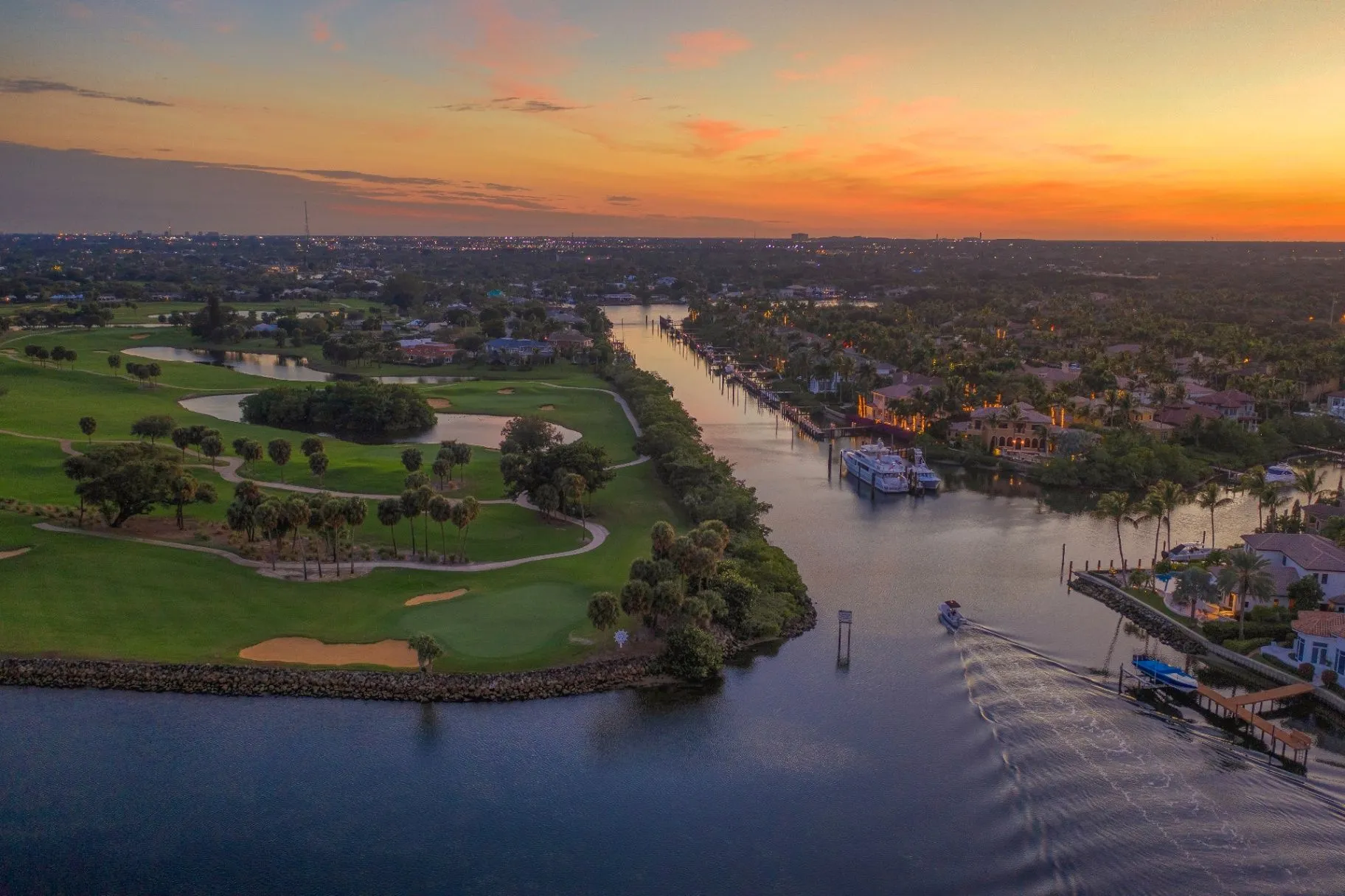 Aerial view of golf fairways beside waterfront homes and a canal in Palm Beach County